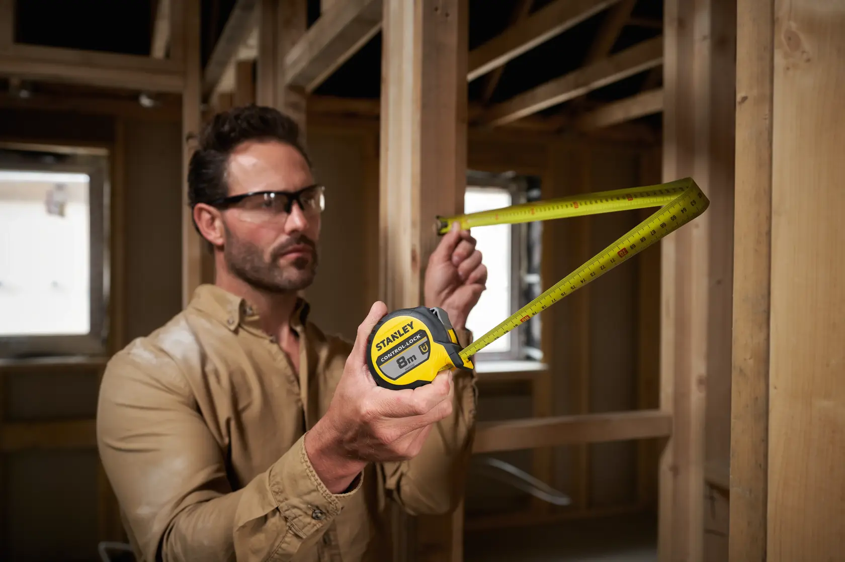 Stanley STHT37232-0 cinta métrica usada para medir un marco de madera en interiores.