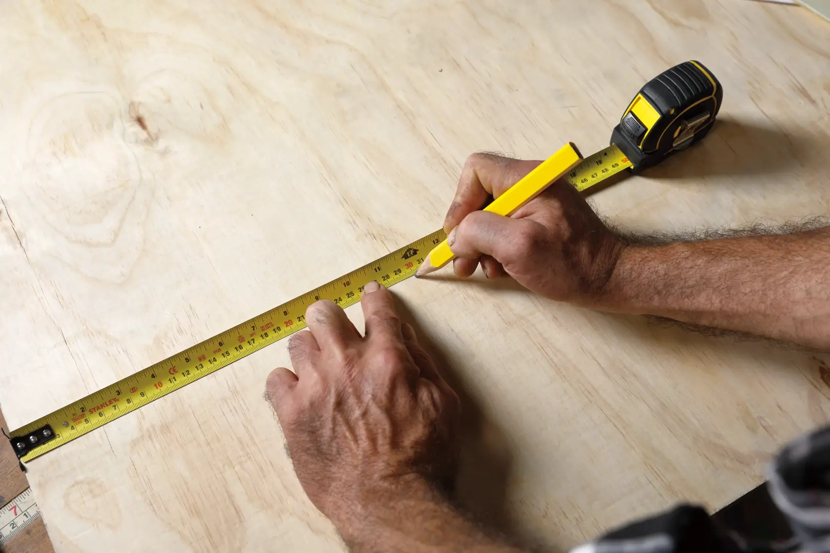 STANLEY 30-626 cinta métrica sobre madera, marcando medidas con lápiz amarillo, fotografía de producto.