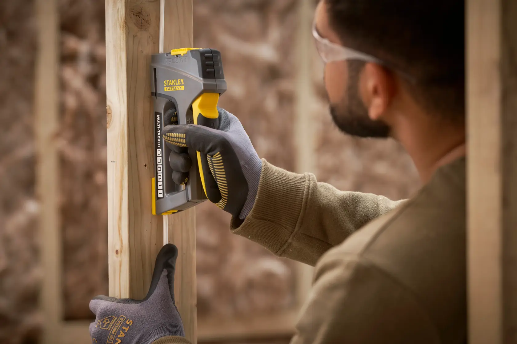 STANLEY FMHT6-70868 pistola de grapas en uso sobre marco de madera, fotografía cercana de herramienta y guante.