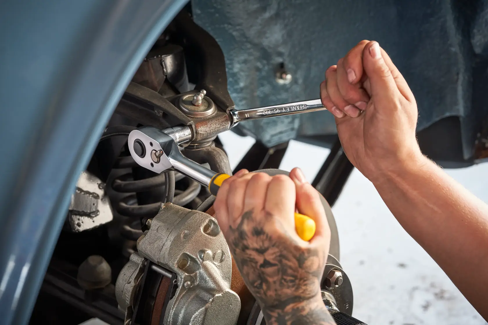 STANLEY STMT82672-0 juego de carraca y vasos usado en suspensión de automóvil, manos con herramientas en primer plano.