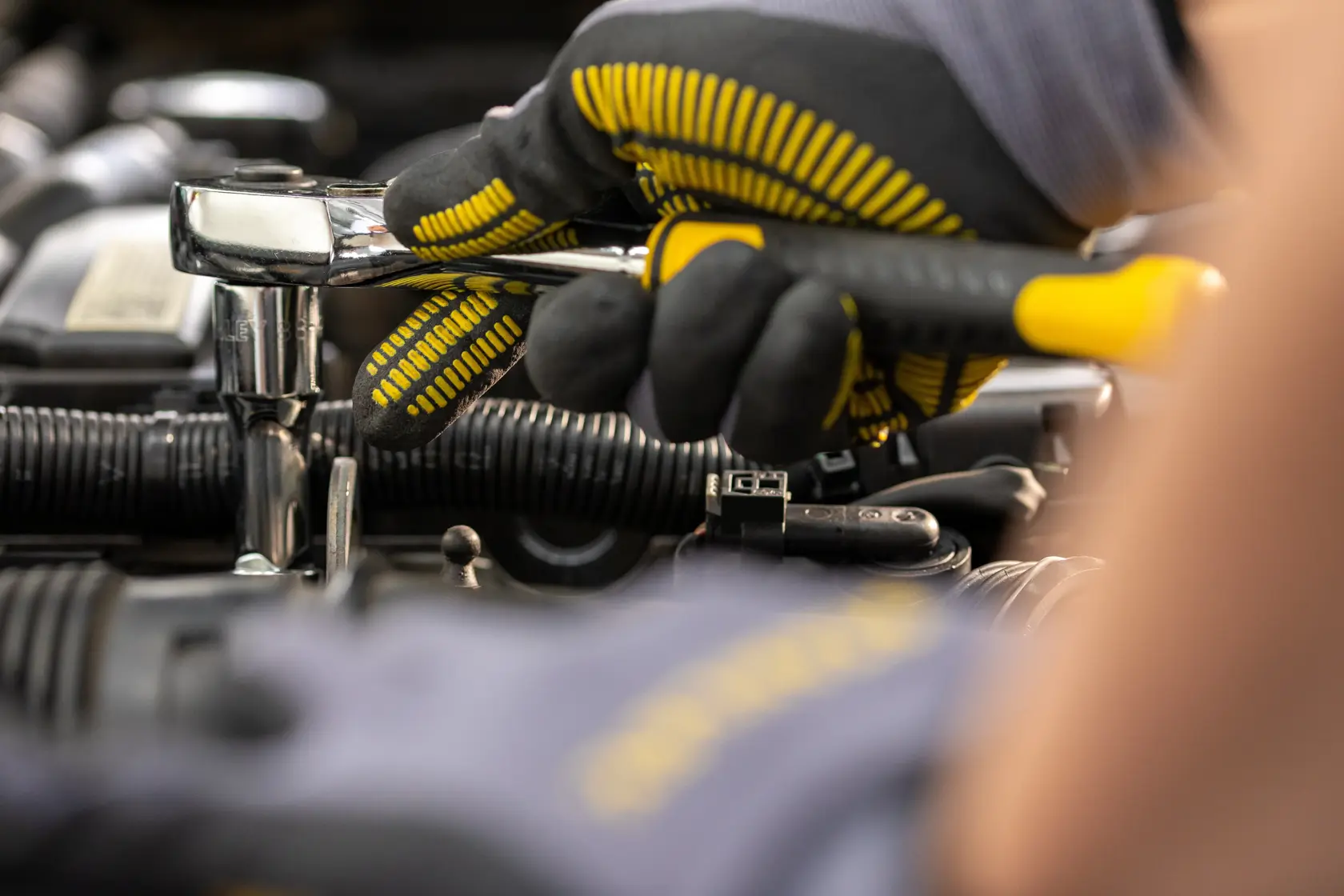 STANLEY STMT82830-1 llave de trinquete usada con guantes en motor automotriz, foto en primer plano.