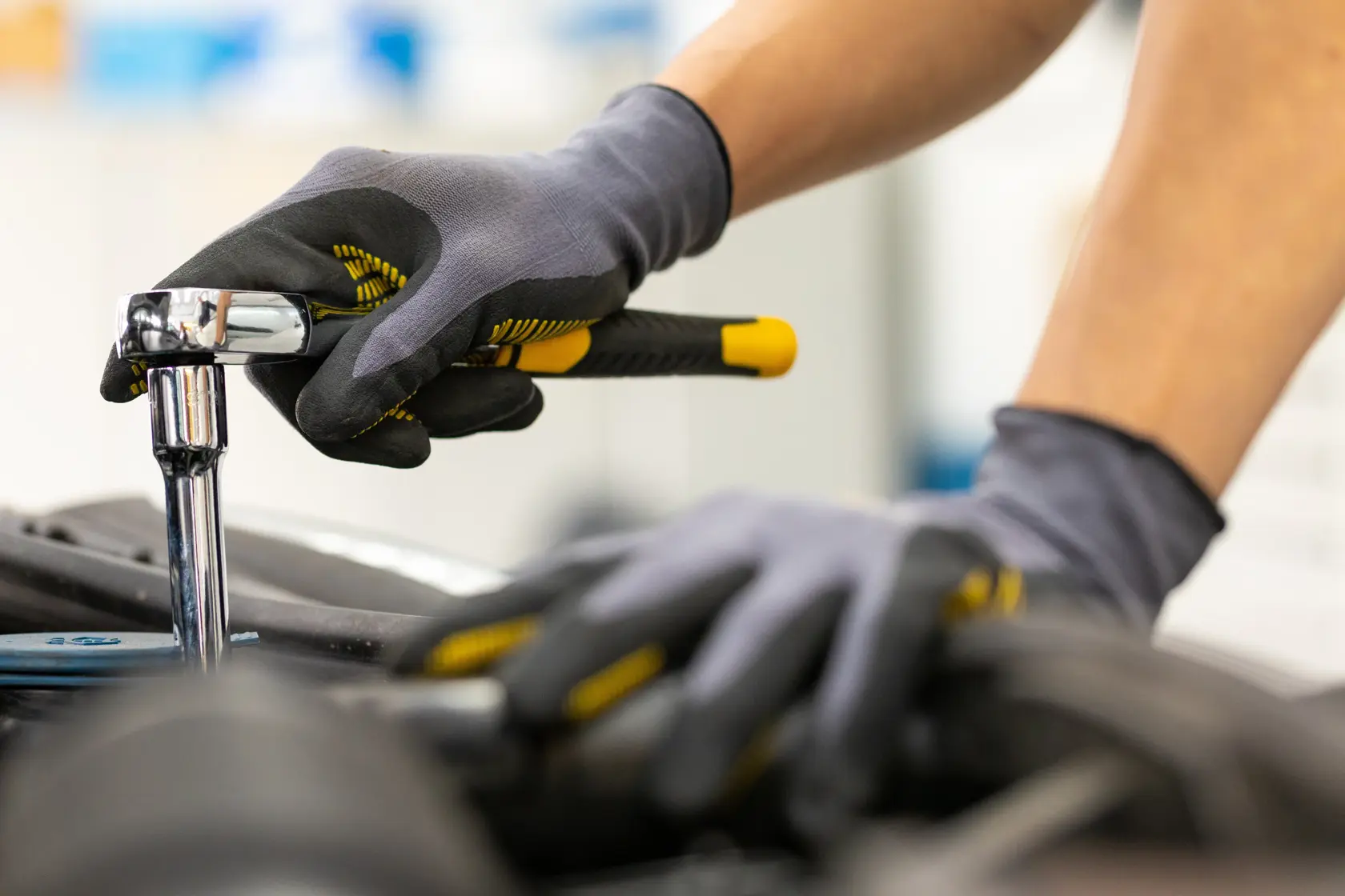 STANLEY STMT82830-1 llave de carraca en uso, primer plano, mango negro y amarillo, guantes de mecánico.